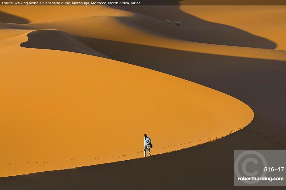 Tourist walking along a giant sand dune, Merzouga, Morocco, North Africa, Africa